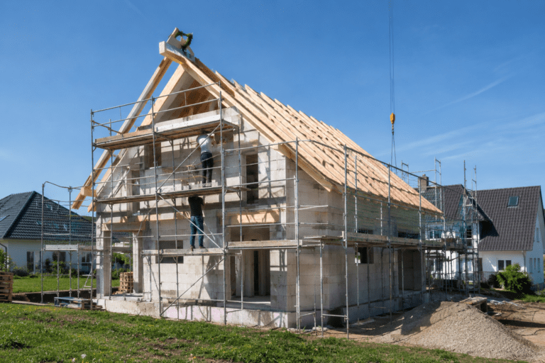 Modernes Einfamilienhaus im Rohbau mit sichtbarer Dachkonstruktion und Bauarbeitern auf der Baustelle – Hausbau Schritt für Schritt dokumentiert.
