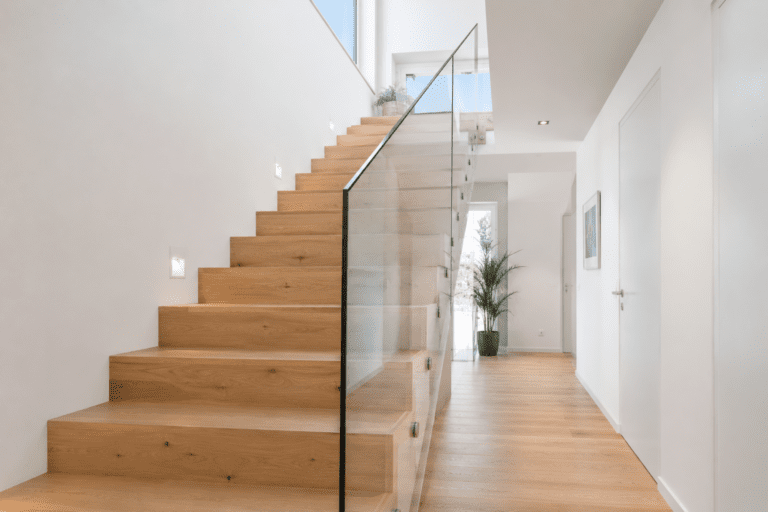 Moderne Eiche-Holztreppe mit minimalistischem Glasgeländer in einem hellen Wohnhaus gemäß DIN 18065 für sichere und komfortable Treppenanlagen.