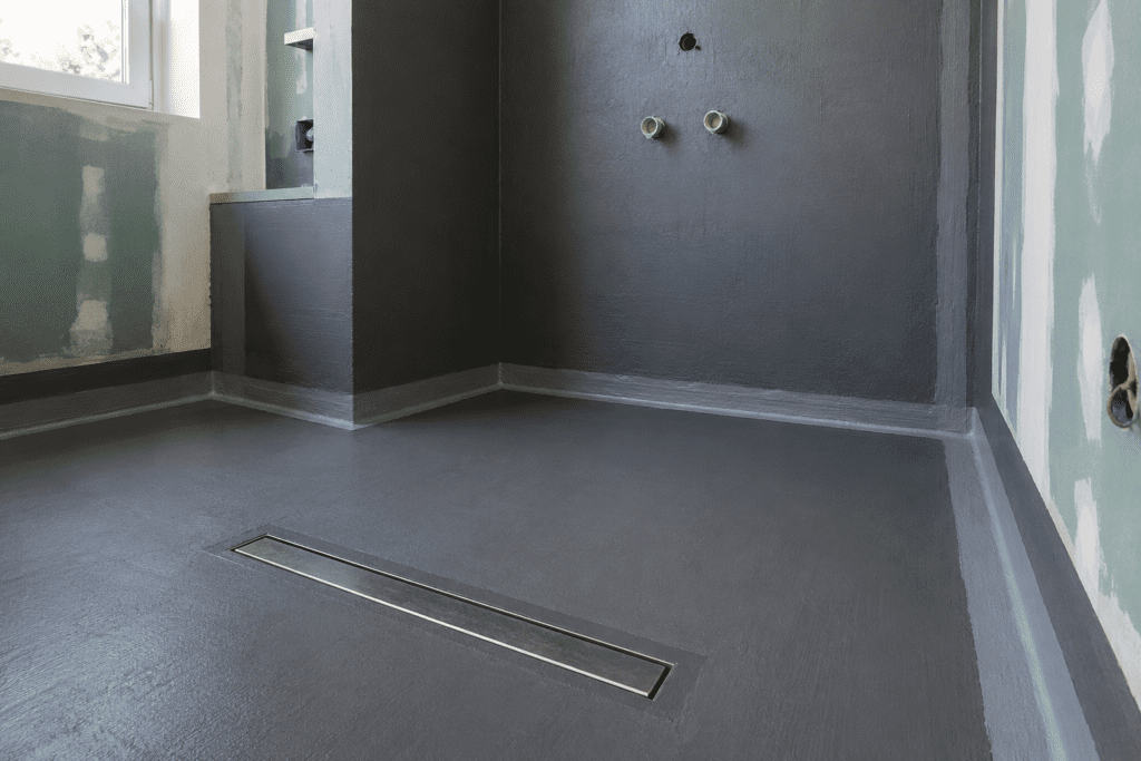 Frisch abgedichtete bodengleiche Dusche mit Dichtschlämme, Linienablauf und Dichtband nach DIN 18534 im Badezimmer-Rohbau.