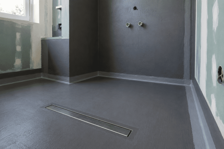 Frisch abgedichtete bodengleiche Dusche mit Dichtschlämme, Linienablauf und Dichtband nach DIN 18534 im Badezimmer-Rohbau.