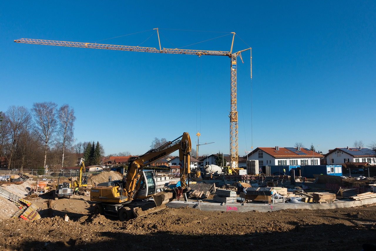 Baustelle mit Bodenplatte, Baugrube, Bagger und Kran – Symbolbild für Hausbau Kosten